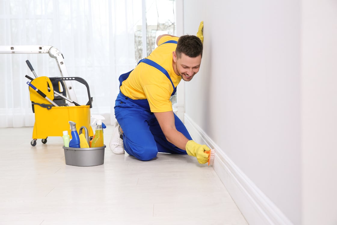 Professional Janitor Cleaning Baseboard with Brush after Renovat